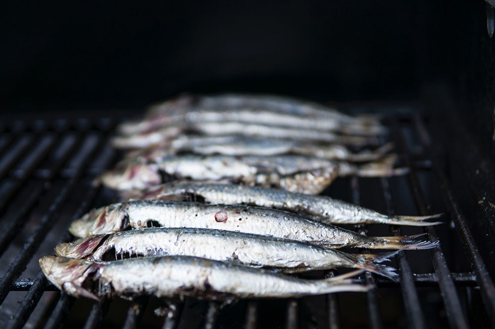 A number of fish are being cooked on a BBQ.