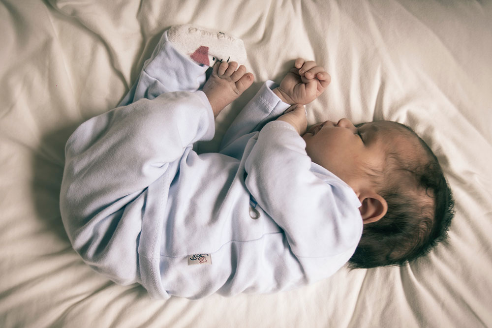 A newborn baby is lay curled up and asleep.