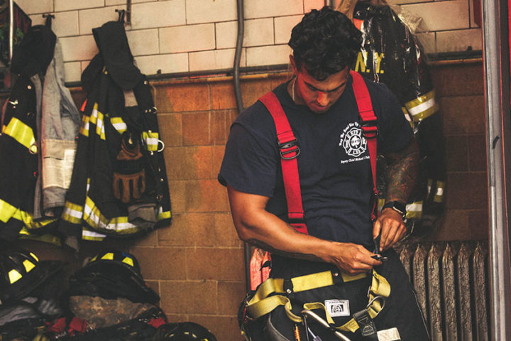 A fireman is putting his protective suit on.