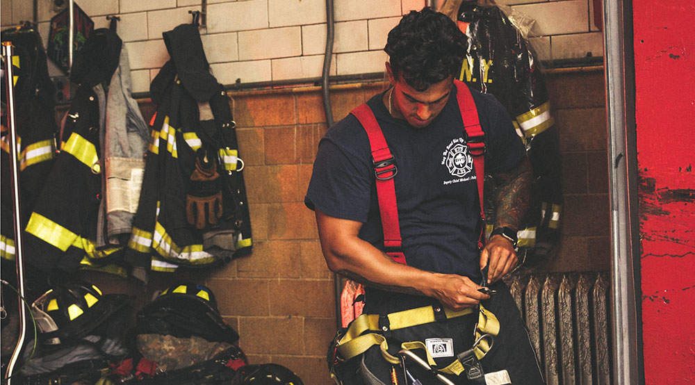 A fireman is putting his protective suit on.