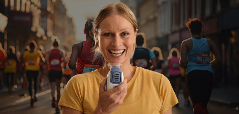 a woman smiling wearing yellow with a breathing trainer