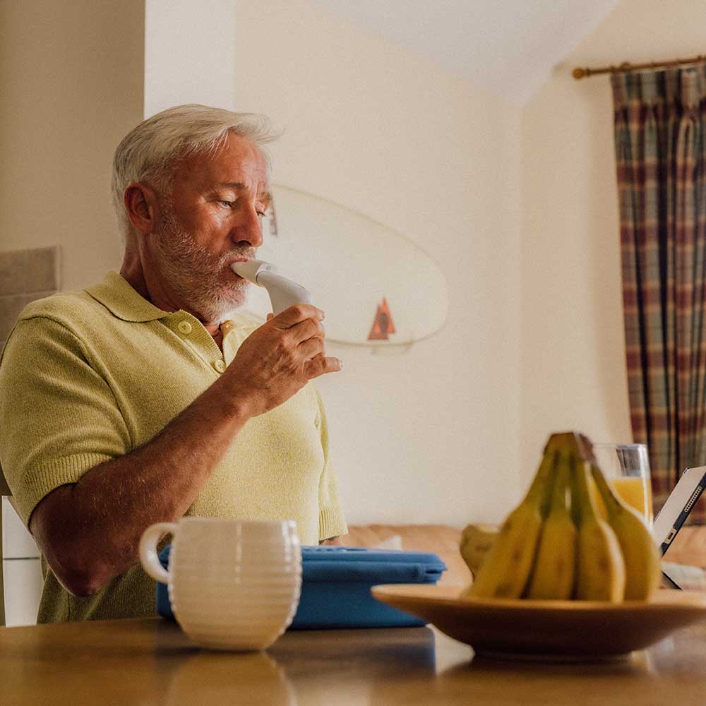 A man sat at a breakfast table using a Plus and a Smart Adaptor