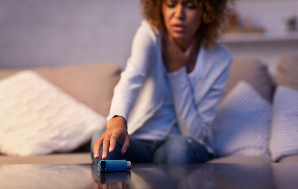 person sitting on sofa reaching for asthma inhaler