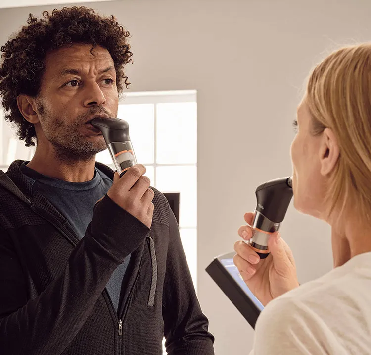 Man and a woman facing eachother using POWERbreathe Plus