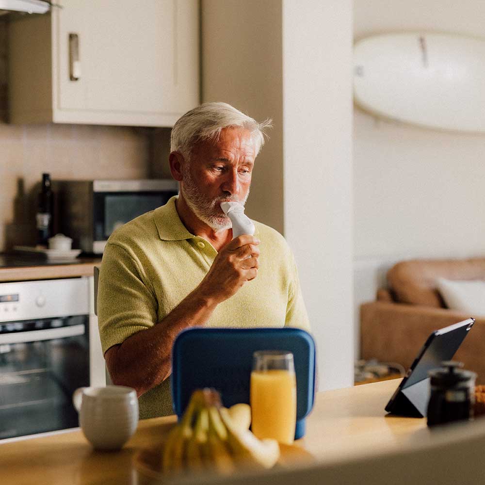 A man sat at a breakfast table using a Plus and a Smart Adaptor