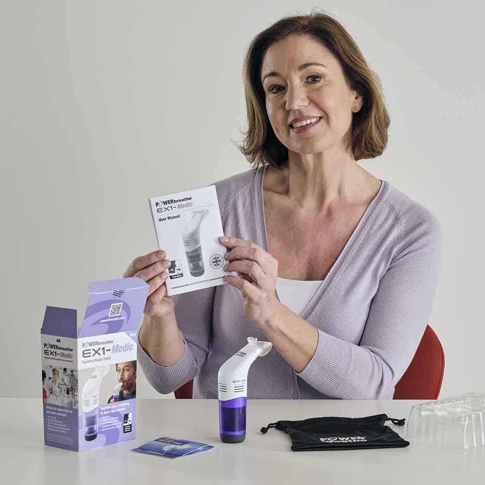 A woman sitting at a desk with all the contents of the EX1 retails box showing