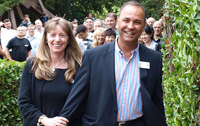 POWERbreathe founders Anne and Harry Brar, smiling at camera in front of group of POWERbreathe distributors.