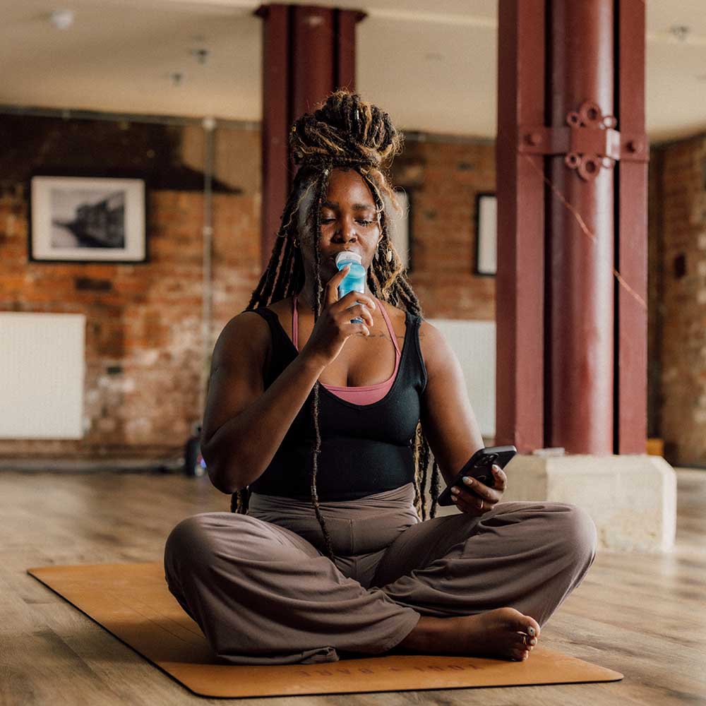 A lady sat on a yoga mat using the Plus and Smart Adaptor