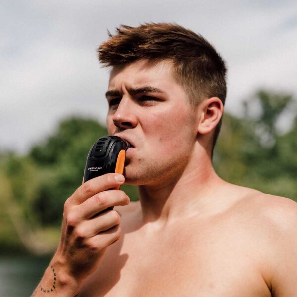 Man standing by a lake using a POWERbreathe K5